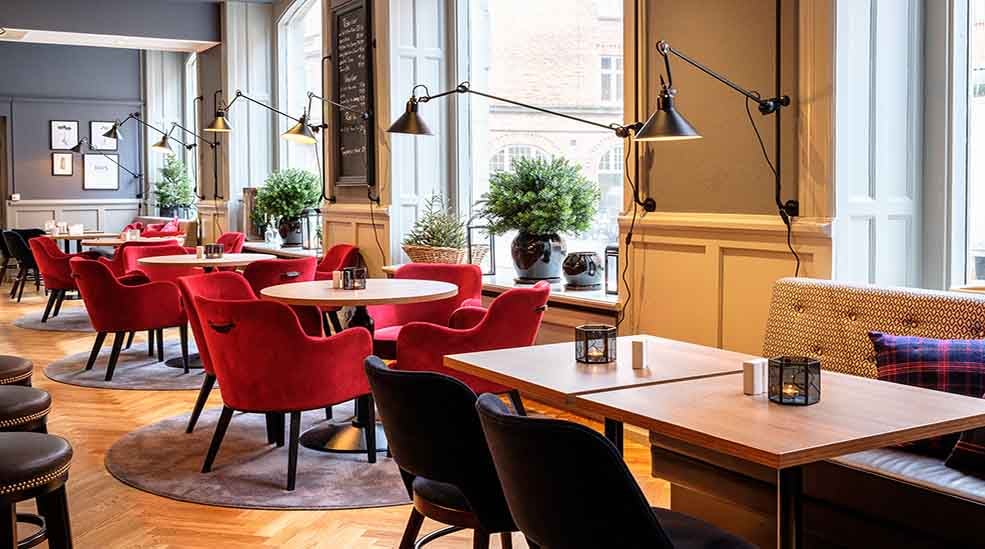 Sitteområde i restauranten med stoler og fine lamper ved vinduet ved Clarion Collection Hotel Temperance i Malmø